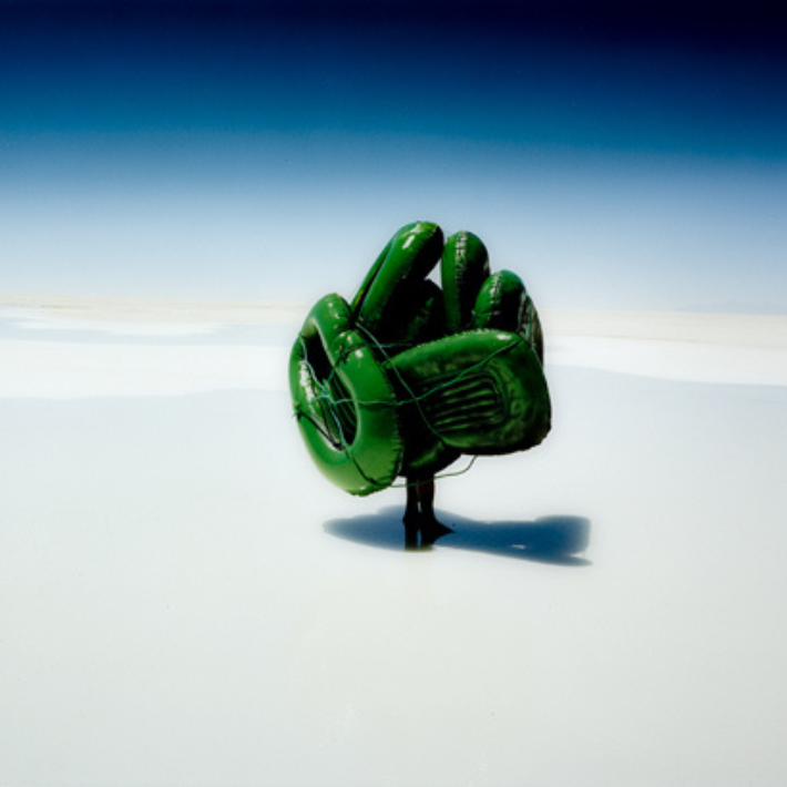 Persoon met groene rubberboten op witte ondergrond en het donkerblauwe/lichtblauwe lucht. Scarlett Hooft Graafland, Seven Steps to Overlapping Beauty, kleurenfoto op dibond, 60 x 75 cm., 2004, kunstcollectie LUMC (Foto Gert Jan van Rooij) Afbeelding:persoon met groene rubberboten op witte ondergrond en het donkerblauwe/lichtblauwe lucht.