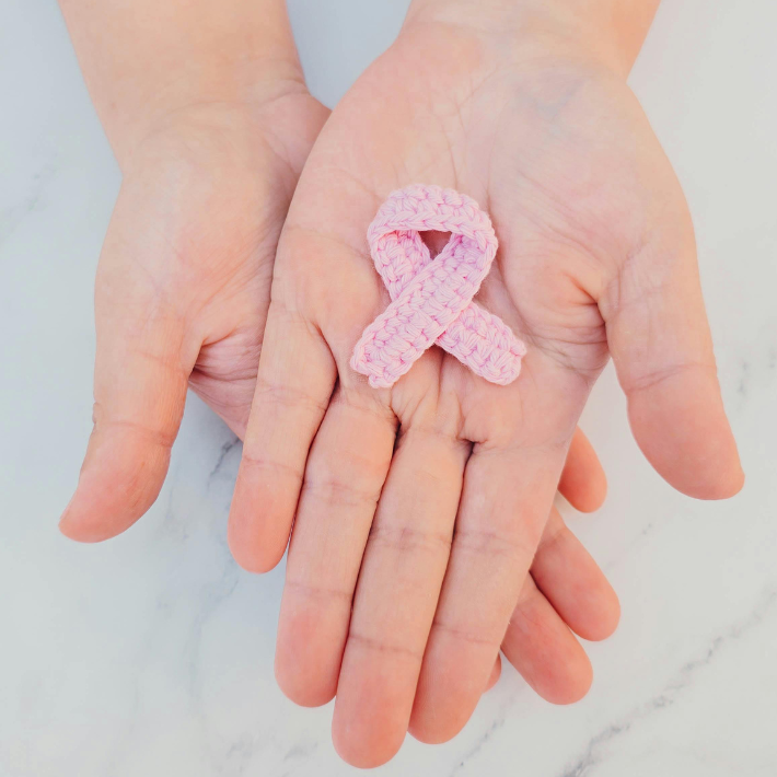 Handen met daarin een roze lint.