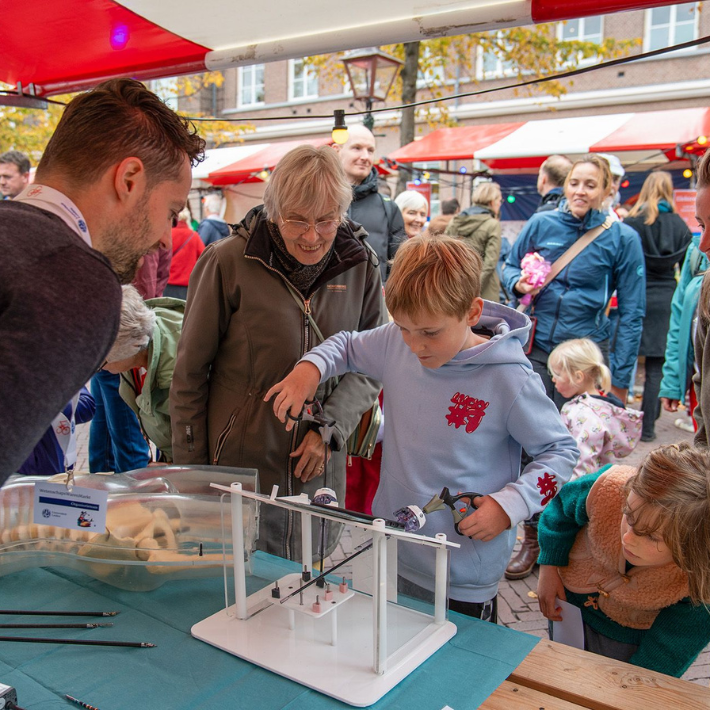 Kind voert een operatie uit met operatietangen terwij hij de bewegingen van de armen volgt via het beeldscherm van een telefoon